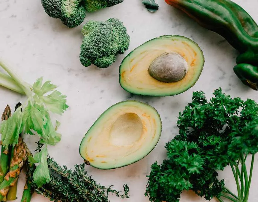 Sliced Avocado next to broccoli and asparagus