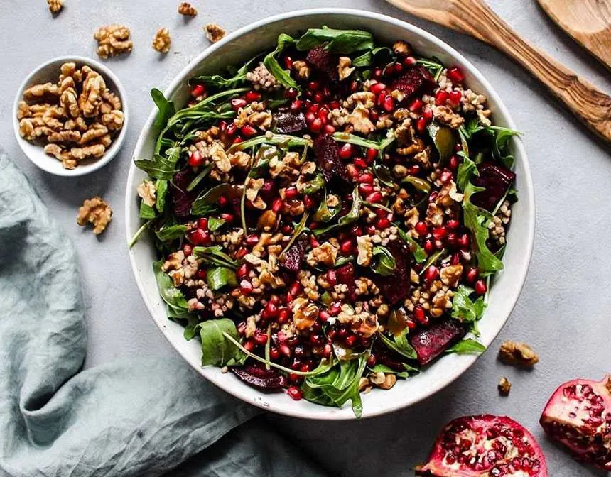 Roasted beetroot pomegranate seeds buckwheat and arugula salad topped with toasted walnuts
