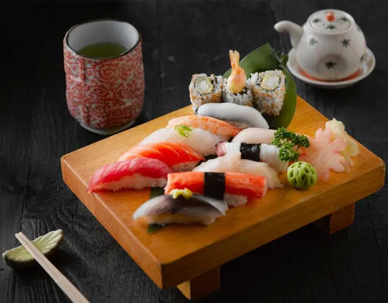 Sushi on brown wooden board with green tea