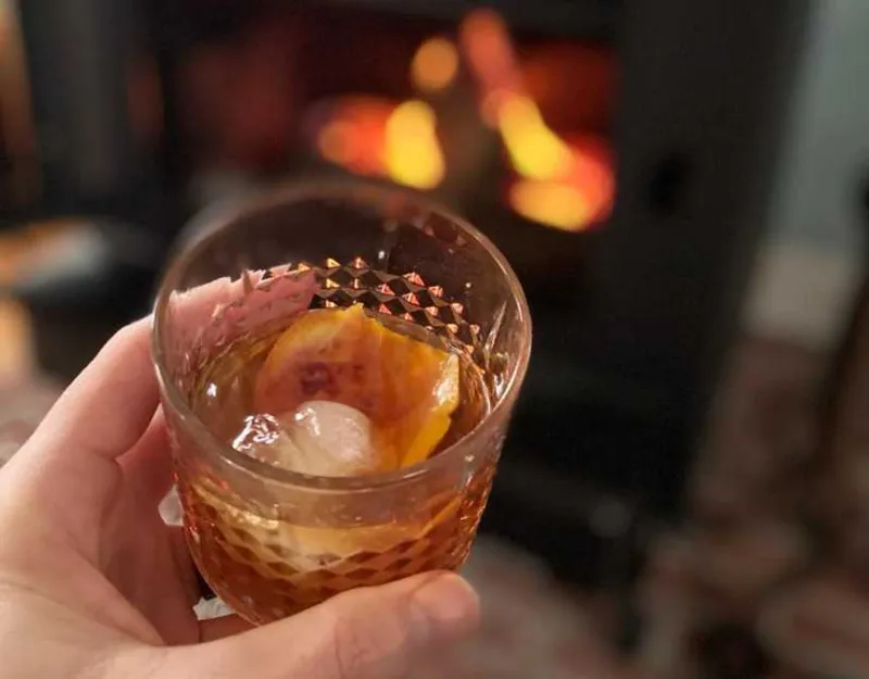 Old fashioned cocktail in front of the fire place