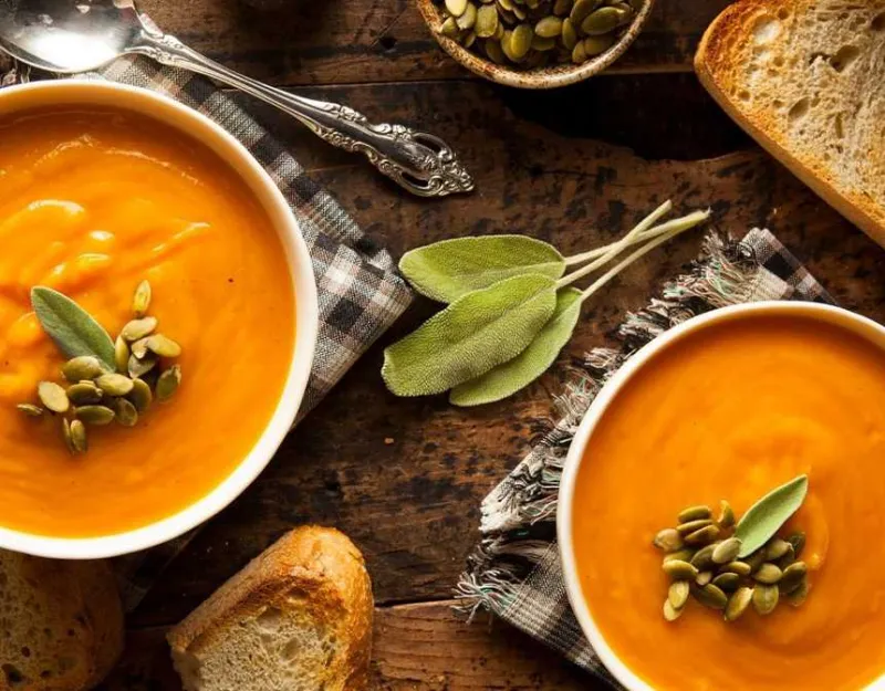 Pumpkin soups on a table with bread