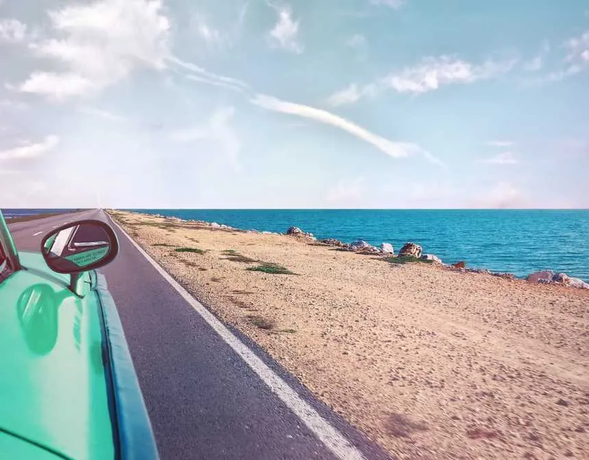 Green car near seashore with blue ocean