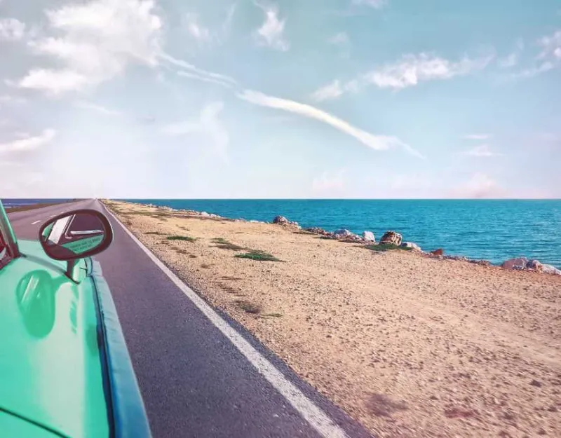 Green car near seashore with blue ocean