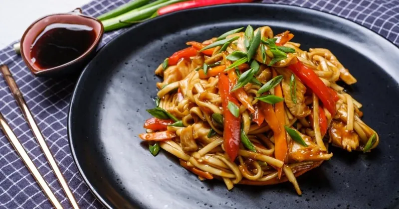 chicken lo mein on a black plate