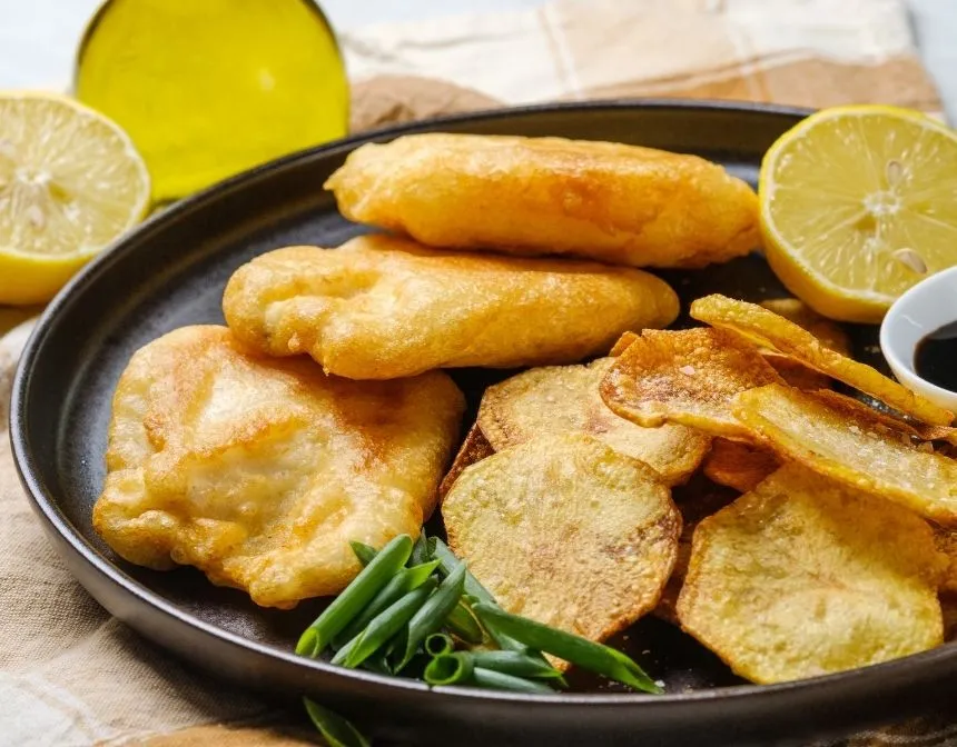 Limonlu bir tabakta balık ve cips ile yeşil soğan